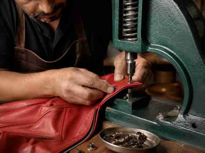 hand-setting rivets and snaps on a custom leather jacket