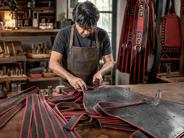custom leather jacket craftsman at workbench with hardware and tools